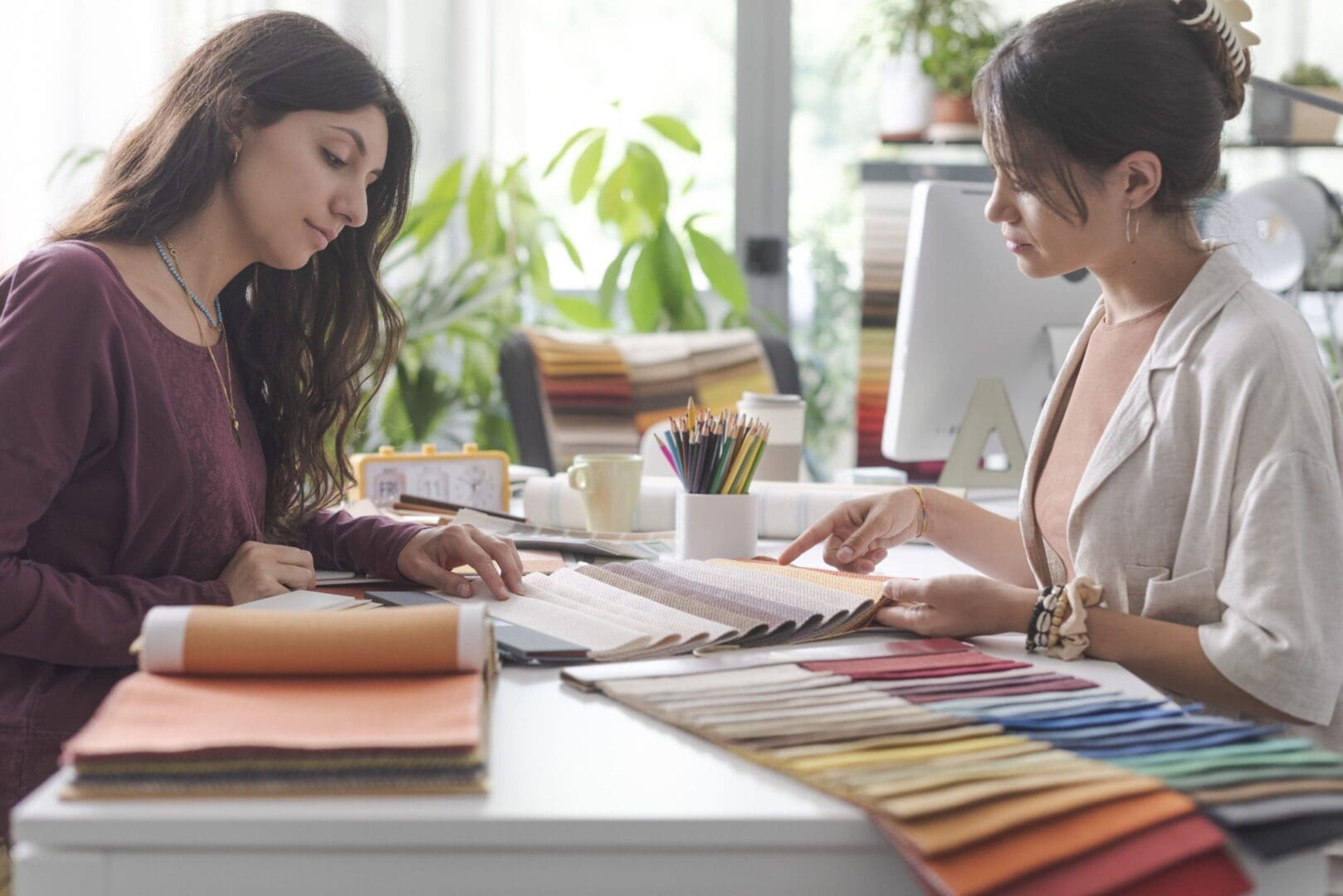 Two women reviewing fabric samples at a table with a color palette.